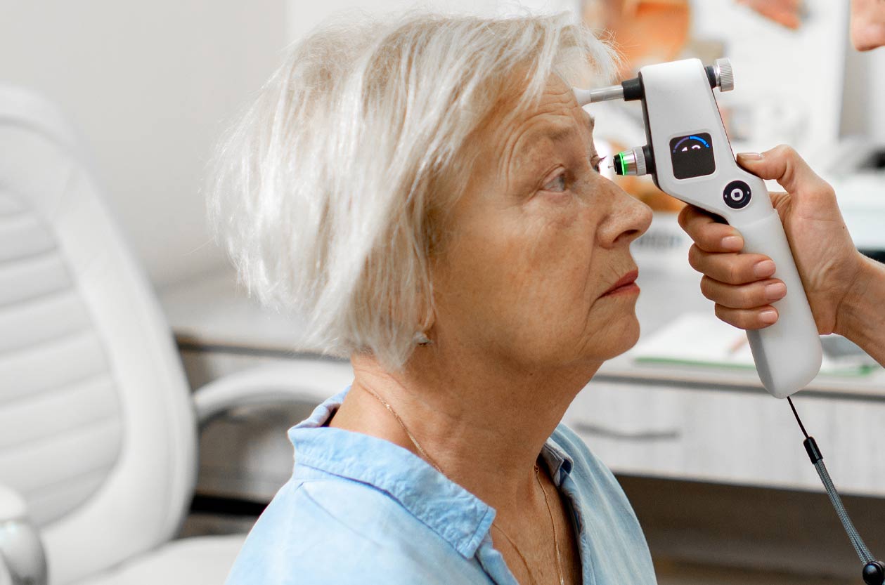 głowa pacjentki oparta na podbródku tonometru przed dyszą dmuchającą powietrzem